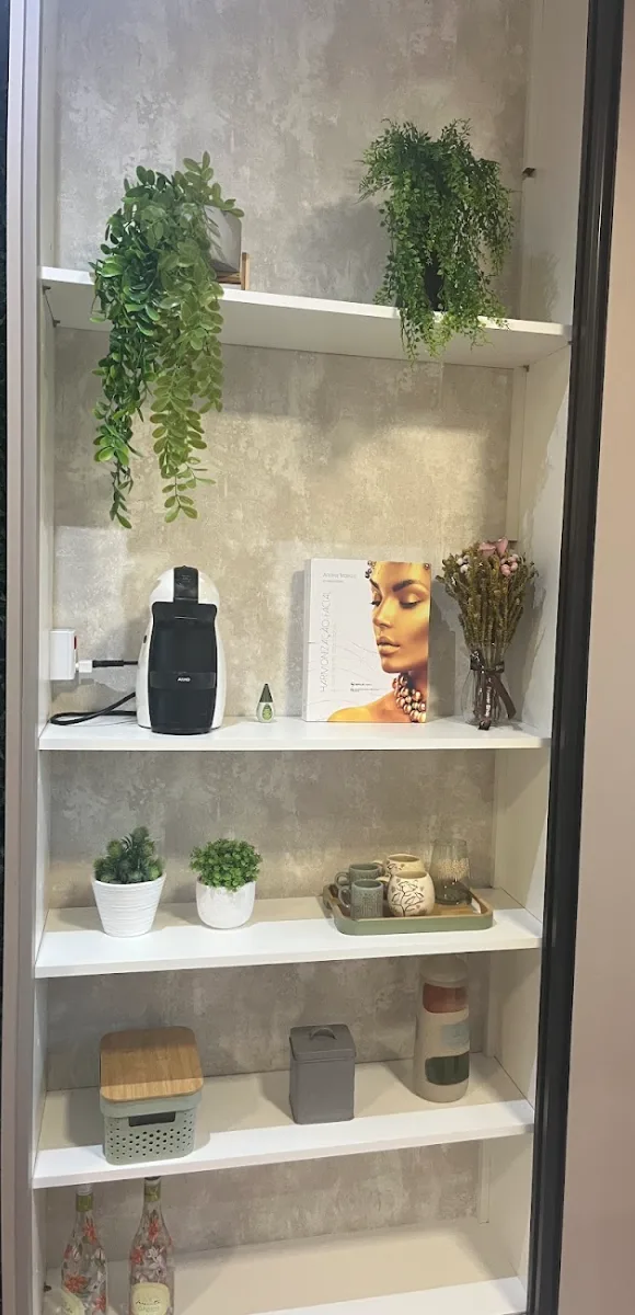 Estante do consultório da Dra. Bárbara Lima, com plantas e livro de harmonização facial